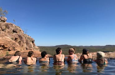 A group of women swim in a natural pool out in nature
