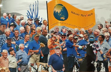 A group of men hold the Albany Men's Shed sign.