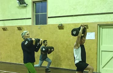 Three people of different ages and genders do exercise together indoors.