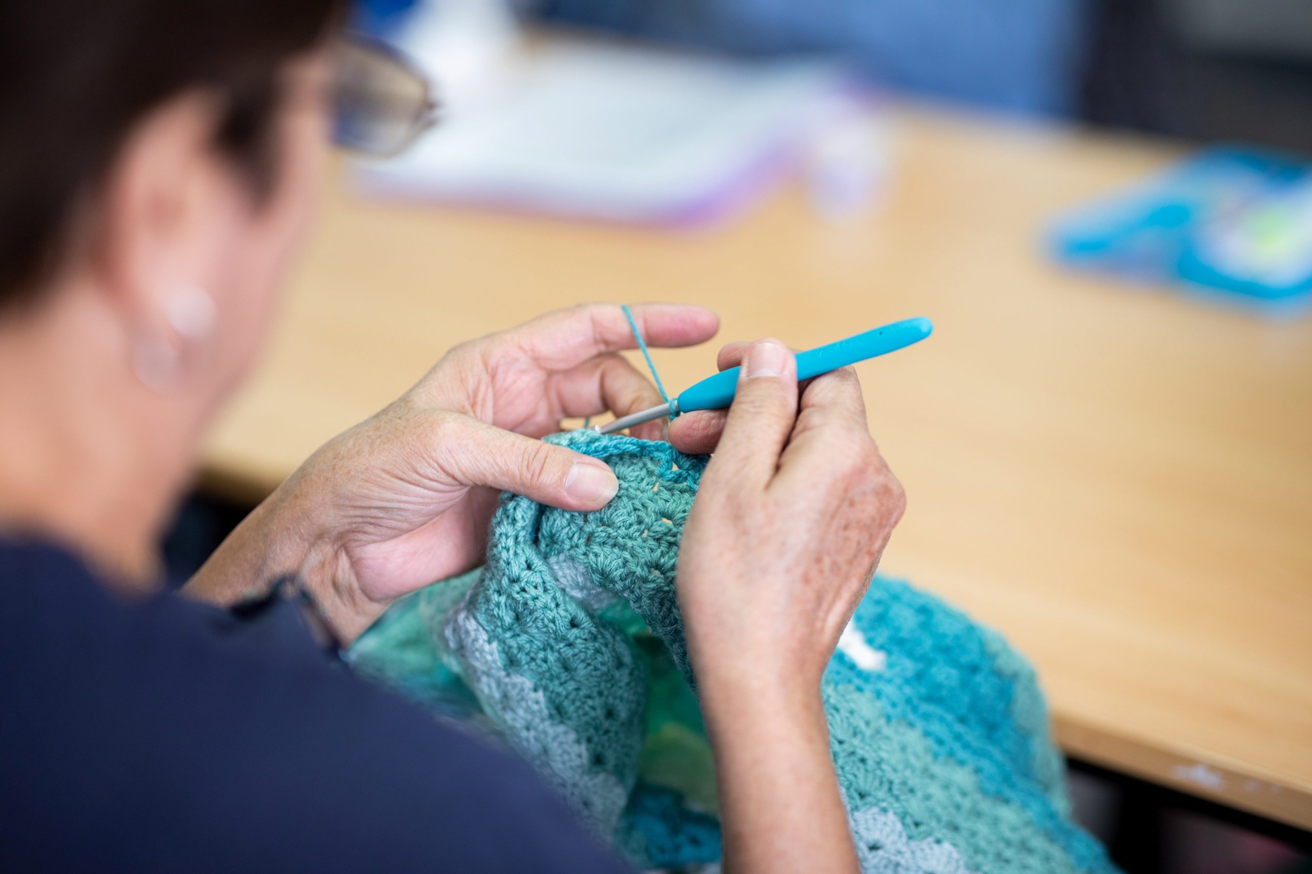 Person crocheting over table.