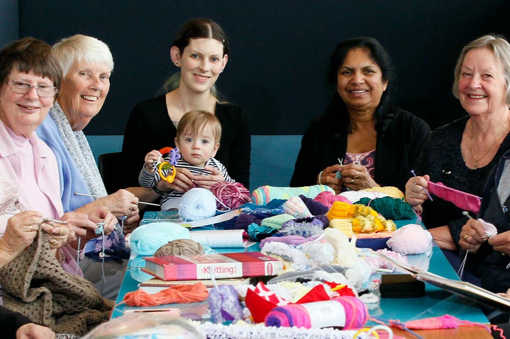 People around table, knitting. 