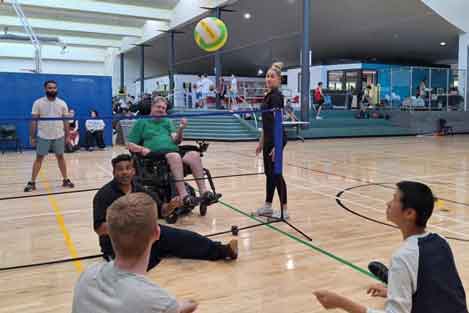 people sitting down, standing and in a wheelchair playing volleyball