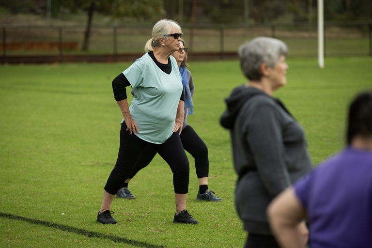 Group of people stretching their legs in a park.