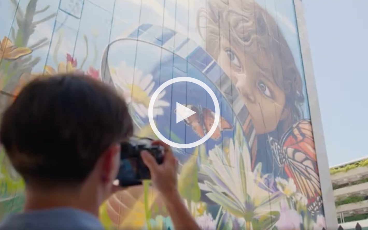 Person photographing large art mural