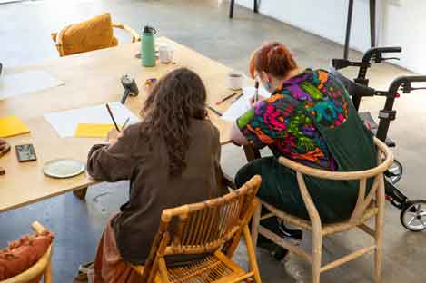people sitting down at a table doing crafts 
