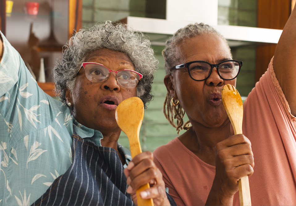 Two happy people singing into wooden spoons