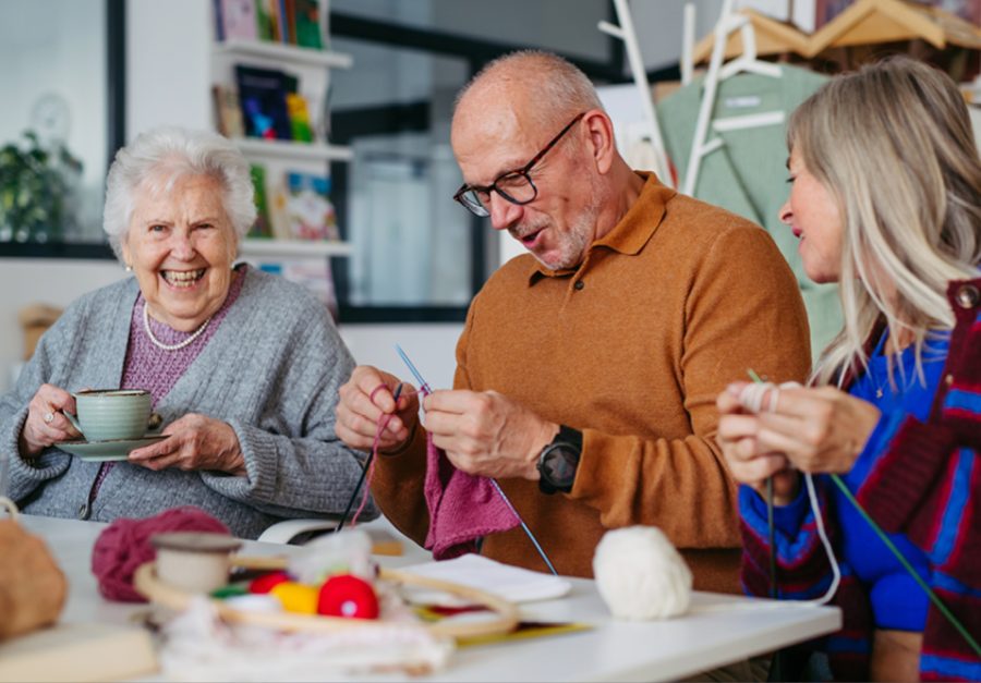 Three people knitting. together and smiing