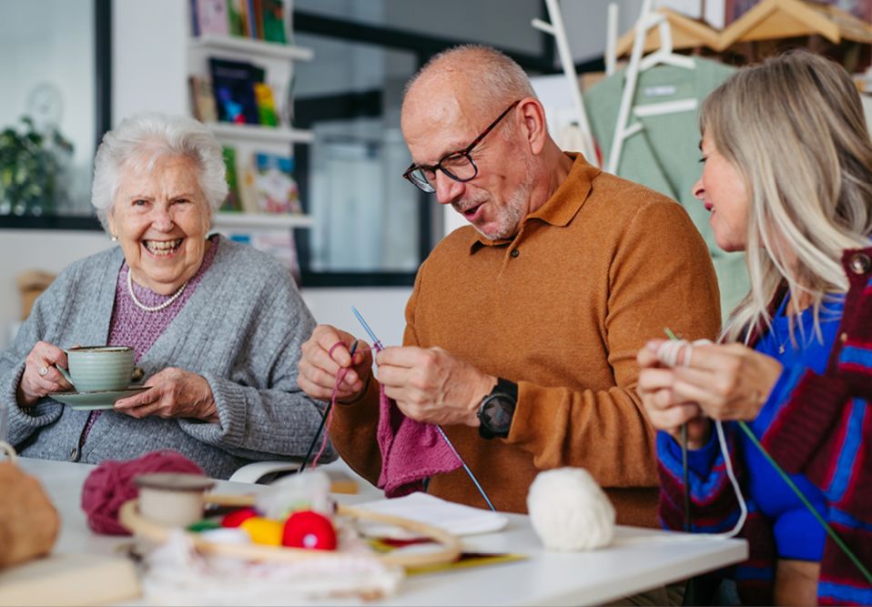 Three people knitting. together and smiing
