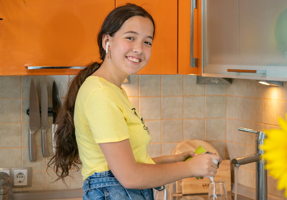 Girl smiling and listening to ear pods while washing up
